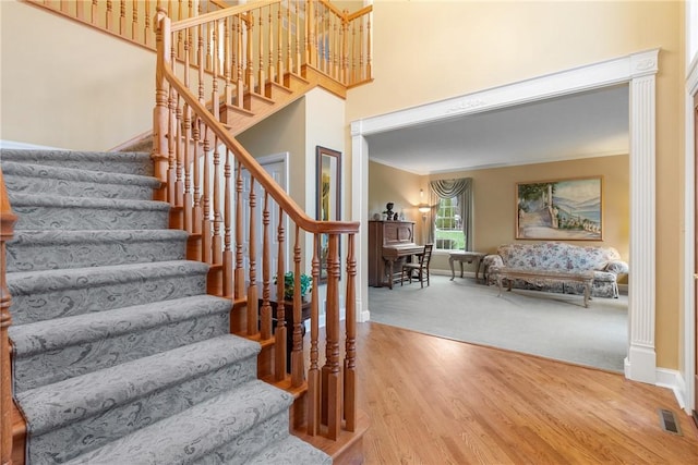 stairway featuring wood finished floors, carpet flooring, baseboards, visible vents, and crown molding