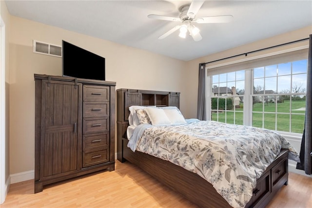 bedroom featuring baseboards, visible vents, a ceiling fan, and light wood-type flooring