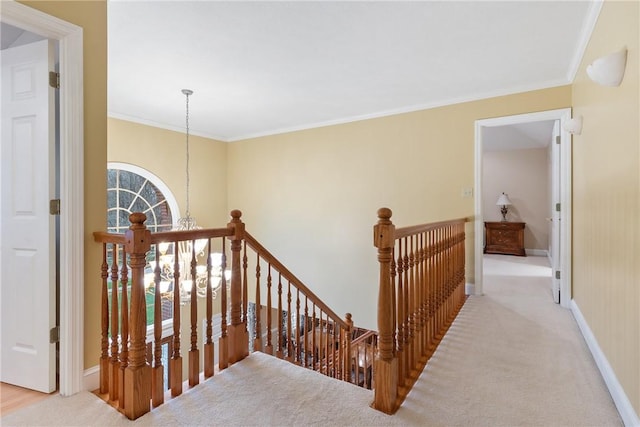 hall with an upstairs landing, baseboards, ornamental molding, and carpet floors