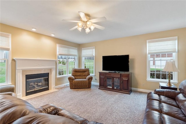 carpeted living room featuring a premium fireplace, a healthy amount of sunlight, a ceiling fan, and baseboards