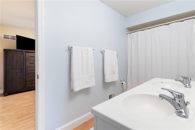 full bath with wood finished floors, visible vents, baseboards, and a sink