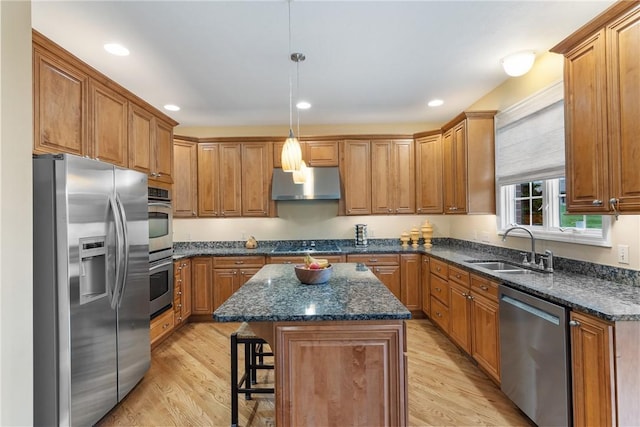 kitchen with under cabinet range hood, brown cabinetry, appliances with stainless steel finishes, and a sink