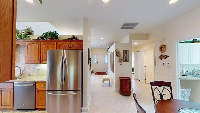 kitchen featuring light tile patterned floors, stainless steel appliances, visible vents, decorative backsplash, and brown cabinets