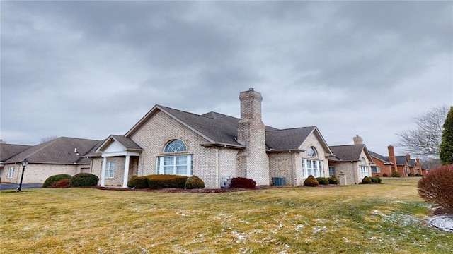 view of front of property with a chimney, a front lawn, and brick siding