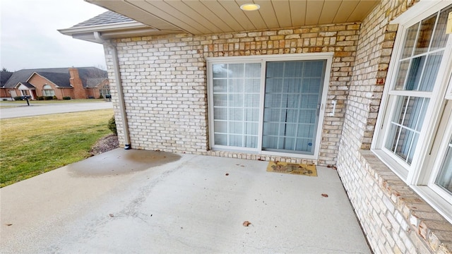 doorway to property with a yard, a patio, and brick siding