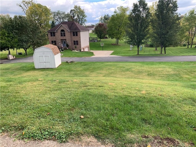 view of yard featuring a garage, a storage shed, aphalt driveway, and an outbuilding