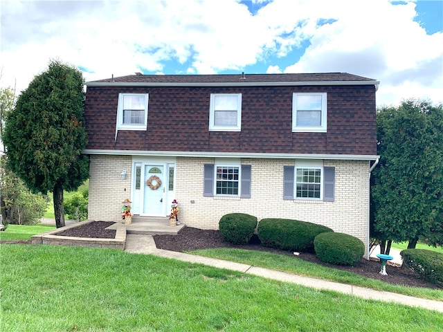 view of front of home featuring roof with shingles, brick siding, a front lawn, and mansard roof