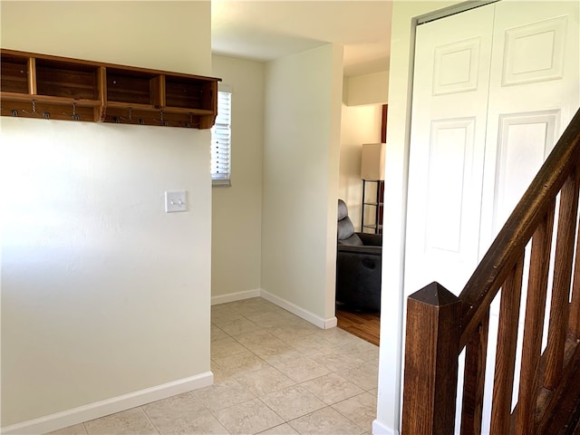 hallway featuring stairs, baseboards, and light tile patterned flooring