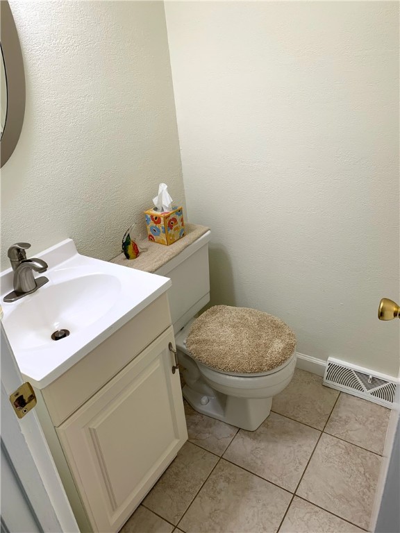 bathroom featuring visible vents, a textured wall, toilet, tile patterned floors, and vanity