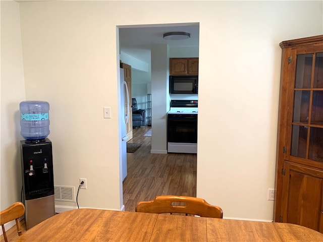 corridor with dark wood-style floors, visible vents, and baseboards