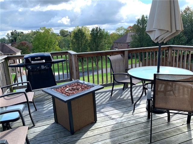 wooden terrace with an outdoor fire pit, grilling area, and outdoor dining space