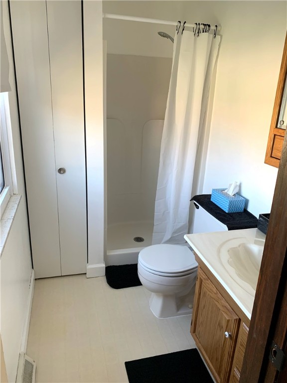 bathroom featuring toilet, visible vents, a shower stall, and vanity