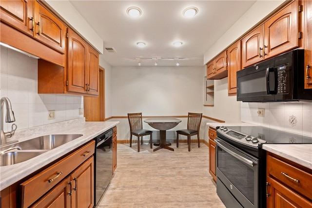 kitchen with a sink, visible vents, light countertops, brown cabinets, and black appliances