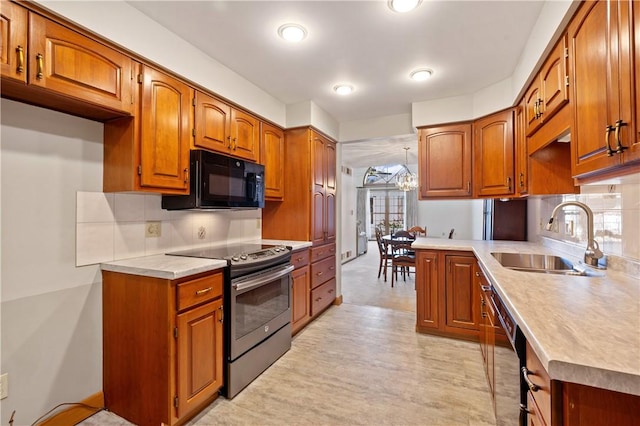 kitchen with brown cabinets, tasteful backsplash, light countertops, a sink, and black appliances