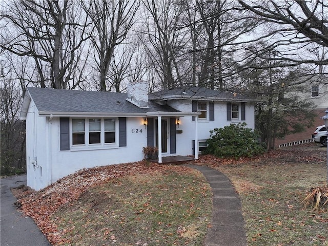 tri-level home featuring a chimney and roof with shingles