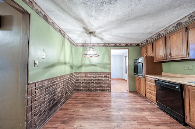 kitchen with black appliances, a textured ceiling, light countertops, and wood finished floors