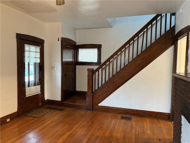 entryway with hardwood / wood-style flooring, baseboards, stairway, and visible vents