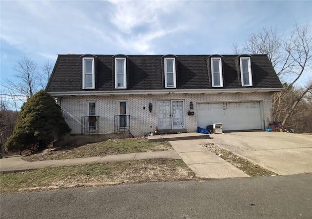 view of front of house with driveway, brick siding, and roof with shingles