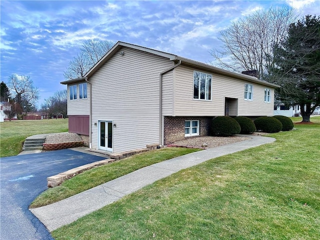 view of property exterior with aphalt driveway, french doors, and a lawn