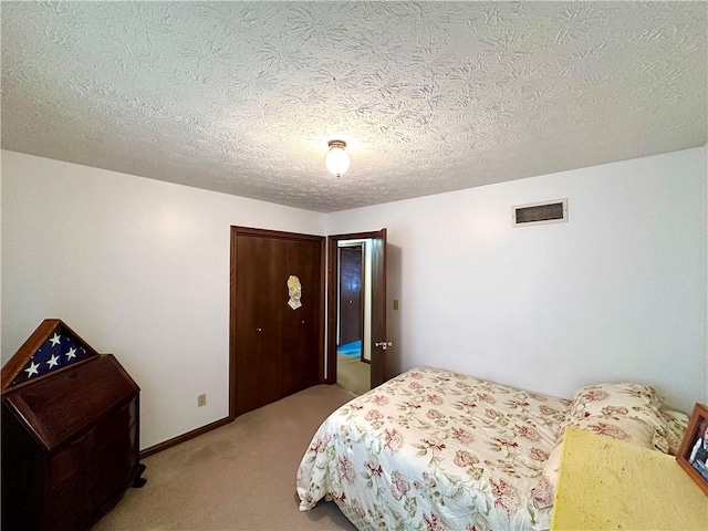 bedroom with light carpet, baseboards, visible vents, a textured ceiling, and a closet