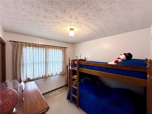 bedroom featuring visible vents, baseboards, a textured ceiling, and light colored carpet