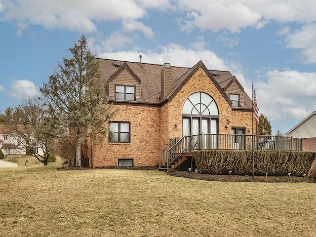 rear view of property featuring a wooden deck, a chimney, a lawn, and brick siding