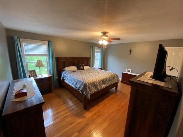 bedroom featuring a ceiling fan, baseboards, and light wood finished floors