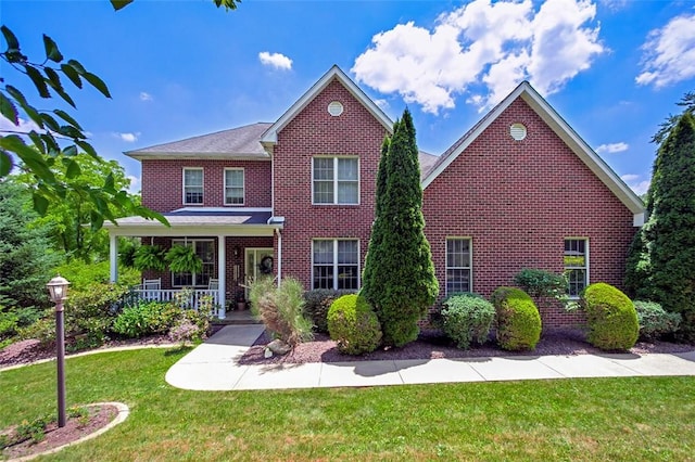 view of front of property with a porch, a front lawn, and brick siding