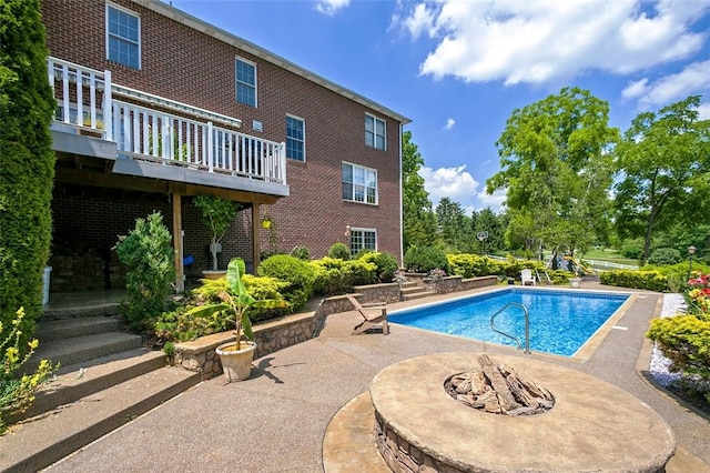 outdoor pool featuring an outdoor fire pit and a patio