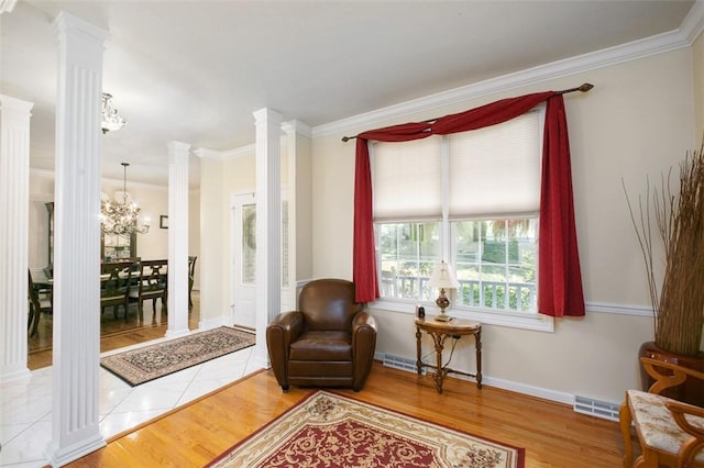 sitting room featuring decorative columns, visible vents, wood finished floors, crown molding, and a notable chandelier