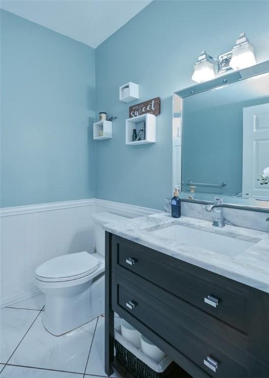 half bathroom featuring a wainscoted wall, vanity, and toilet