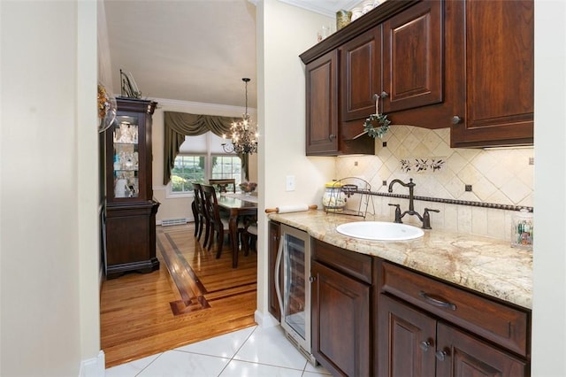 kitchen with light stone countertops, beverage cooler, ornamental molding, and a sink