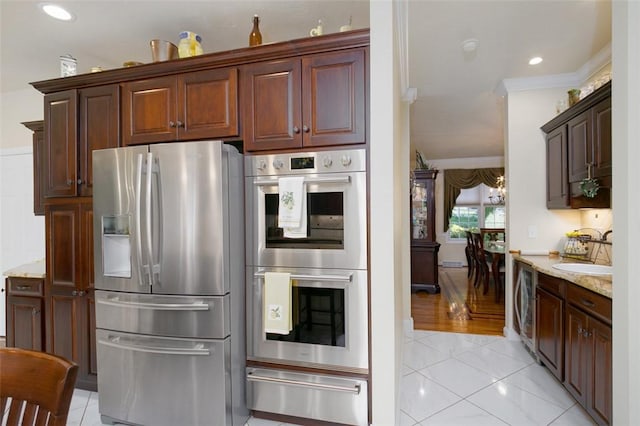 kitchen with a sink, appliances with stainless steel finishes, ornamental molding, light stone countertops, and a warming drawer