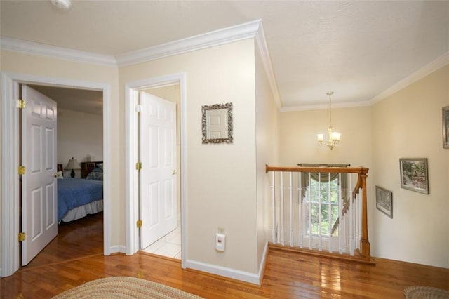 hallway featuring crown molding, an inviting chandelier, an upstairs landing, wood finished floors, and baseboards