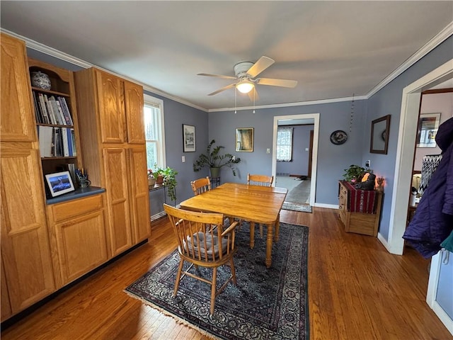 dining area featuring a wealth of natural light, dark wood finished floors, crown molding, and baseboards