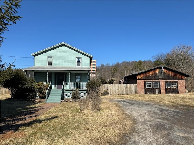 view of front of property with covered porch, brick siding, and fence