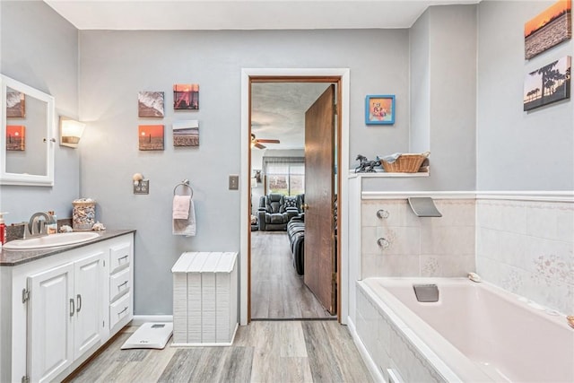 bathroom with a bath, ceiling fan, wood finished floors, and vanity