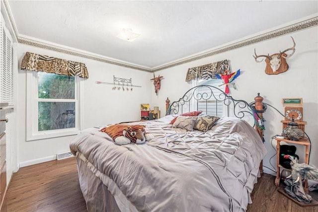 bedroom with baseboards, crown molding, visible vents, and wood finished floors