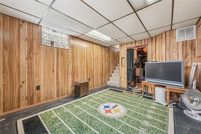 interior space featuring baseboards, visible vents, wooden walls, and a drop ceiling