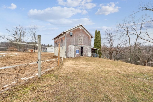 view of property exterior with an outbuilding, a lawn, a barn, and fence