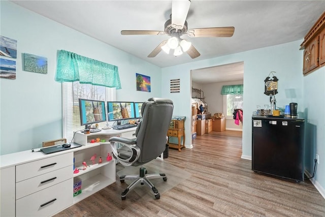 home office with light wood-style flooring, baseboards, and a ceiling fan