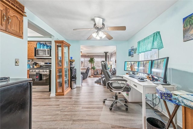 office with light wood-style floors and ceiling fan