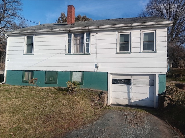 view of front of house with an attached garage, a chimney, and a front yard