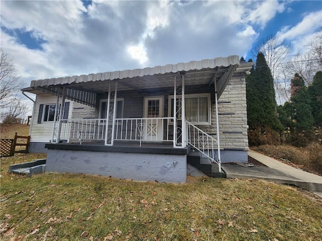 back of property featuring a porch and stone siding