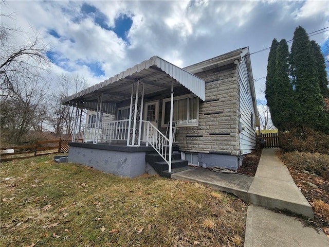 view of front of house featuring a porch, stone siding, and fence