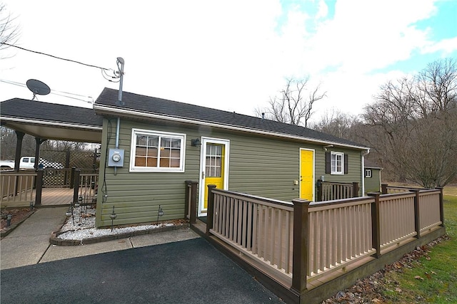 back of property with a deck and roof with shingles