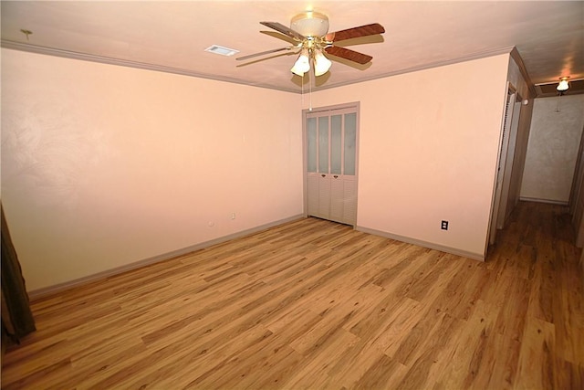 spare room with baseboards, visible vents, crown molding, and light wood finished floors