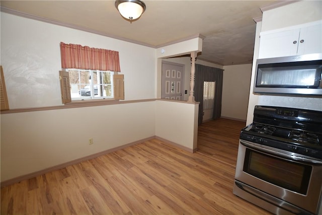 kitchen with appliances with stainless steel finishes, white cabinets, ornamental molding, and light wood-style flooring