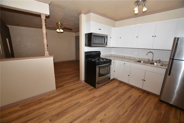 kitchen featuring appliances with stainless steel finishes, a sink, light wood-style flooring, and a ceiling fan