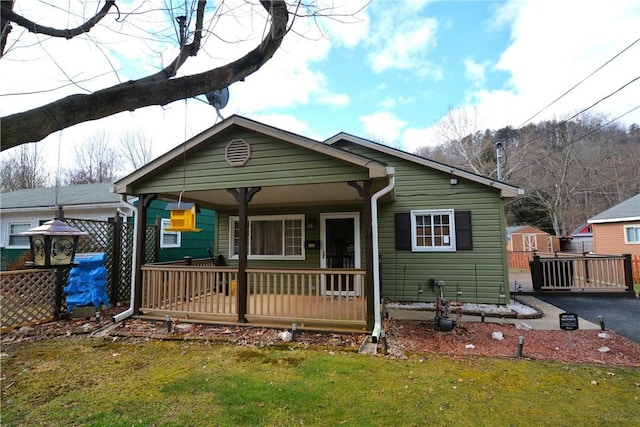 view of front facade with driveway, a porch, a front lawn, and fence